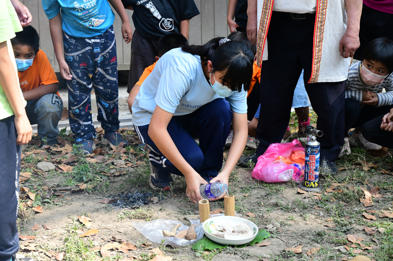 A student pours an offering during the weeding ceremony.