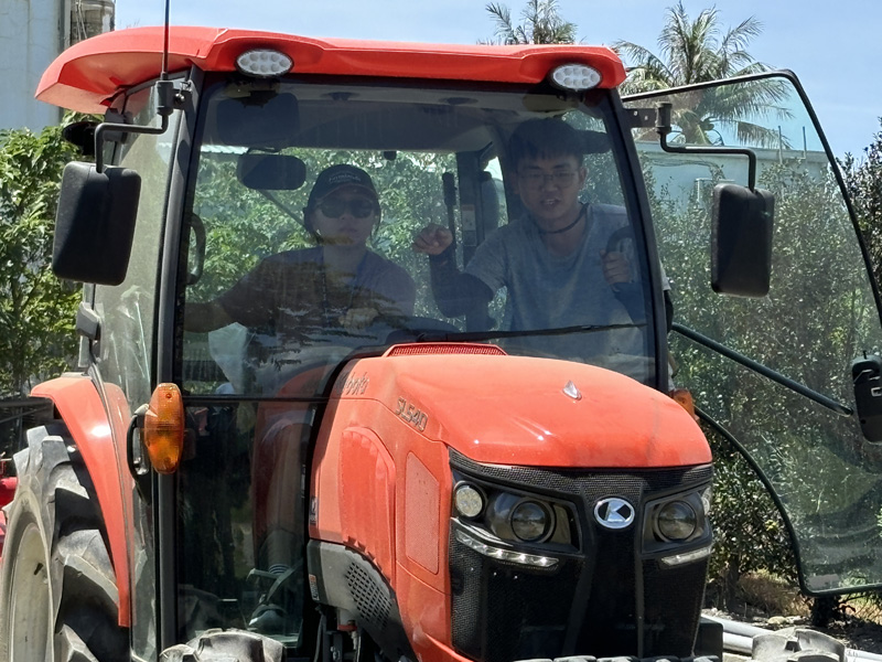 A participant listens to an assistant instructor while driving a tractor.