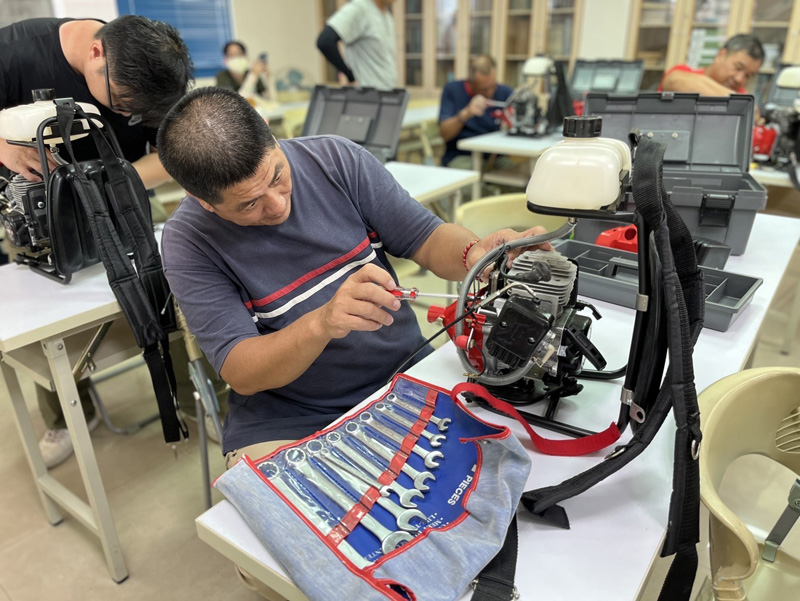 A student tries his hand at disassembling and maintaining a backpack brushcutter.