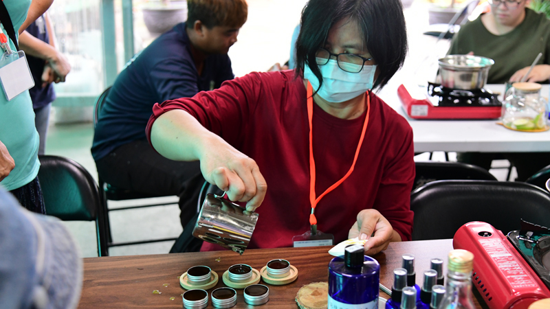 A participant processing herbs into a marketable product.