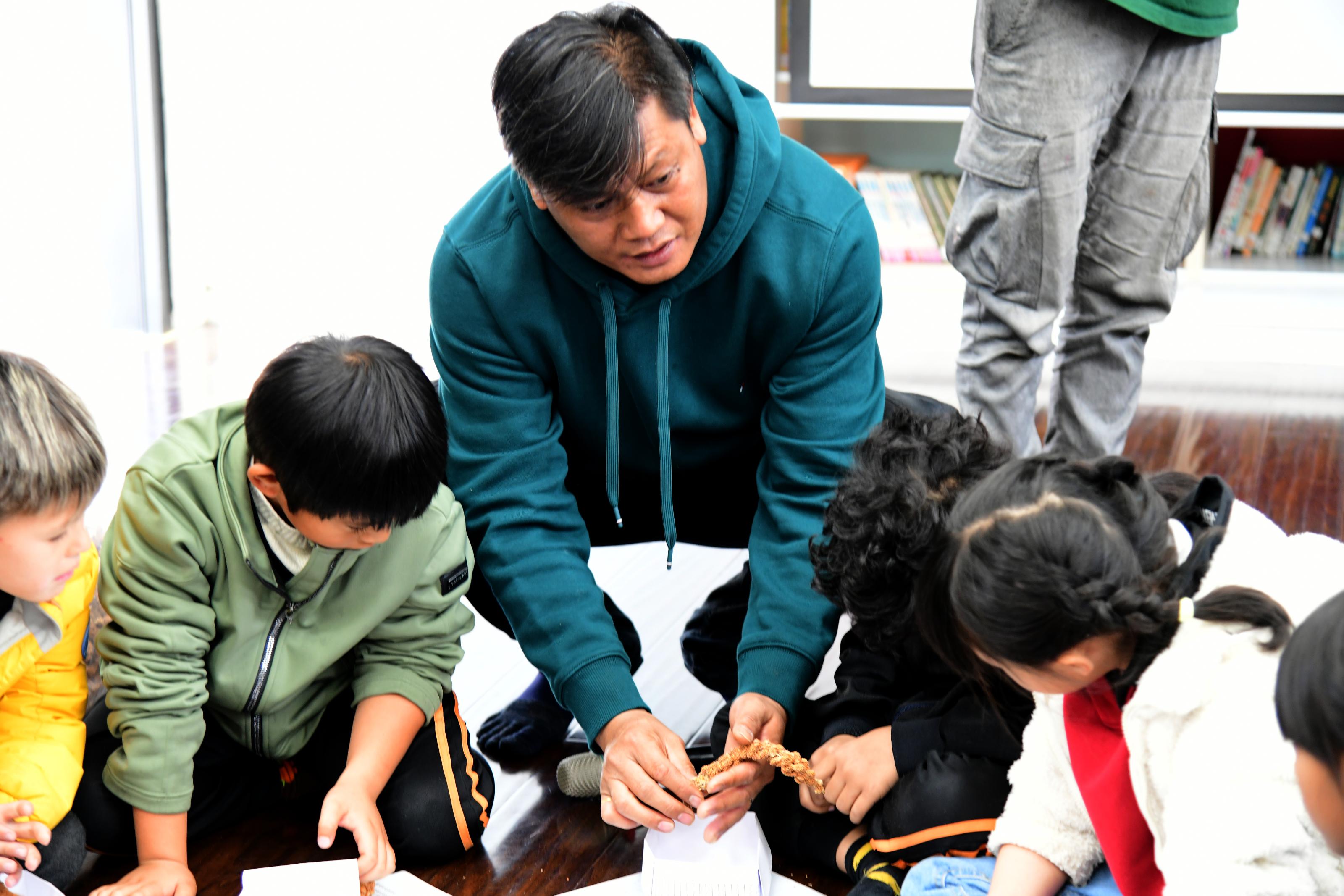 The instructor shows students how to remove millet husks.