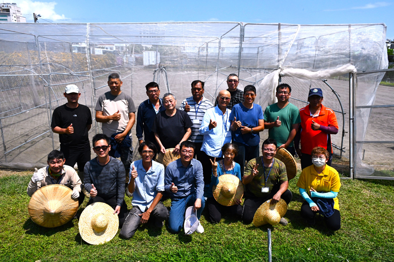 Group photo of participants and a net house they built.