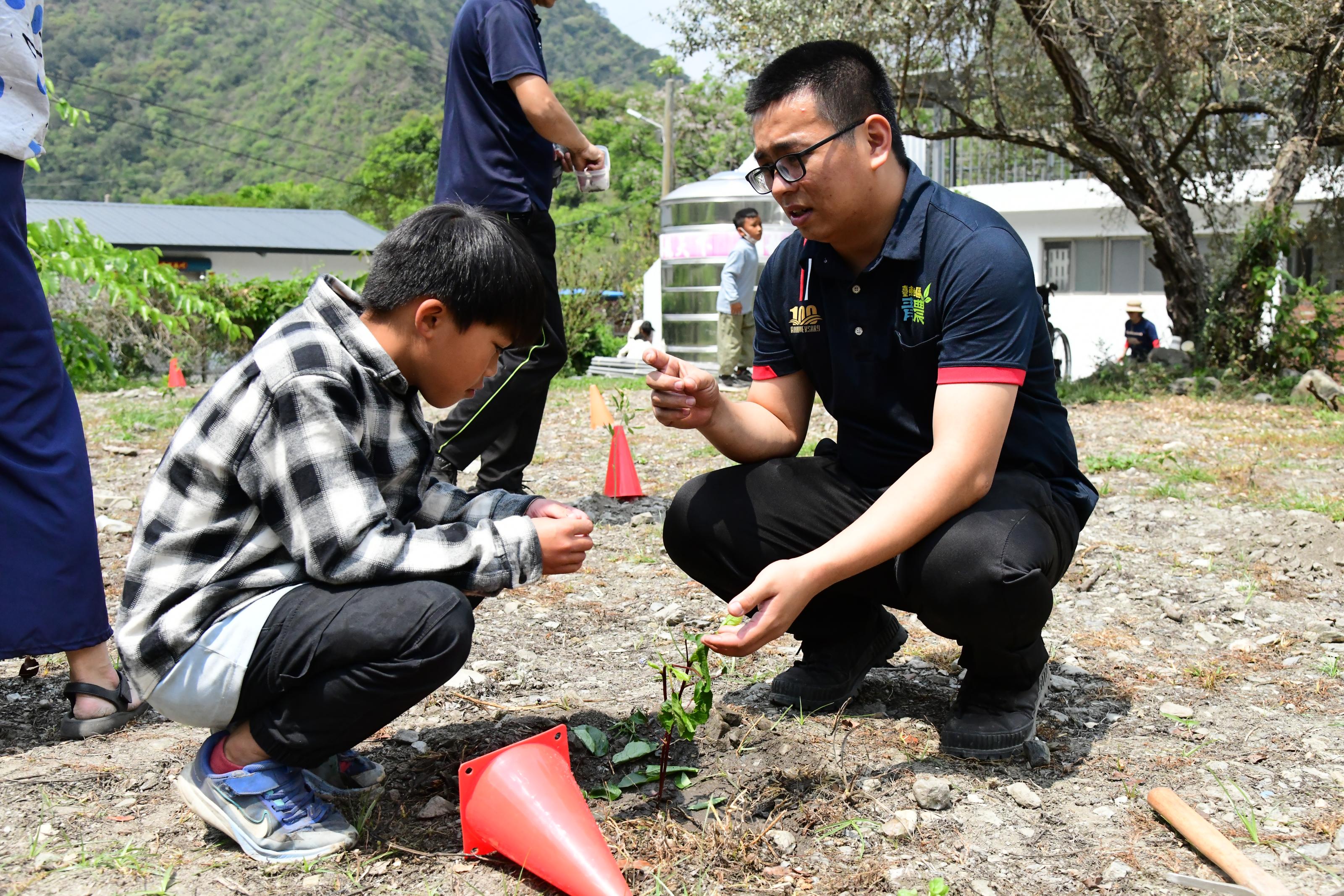 The instructor teaches a student how to plant a roselle seedling.